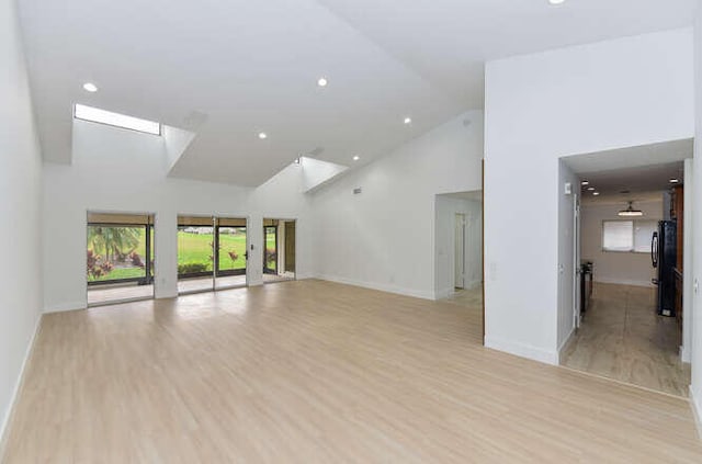 unfurnished room featuring light hardwood / wood-style floors and high vaulted ceiling