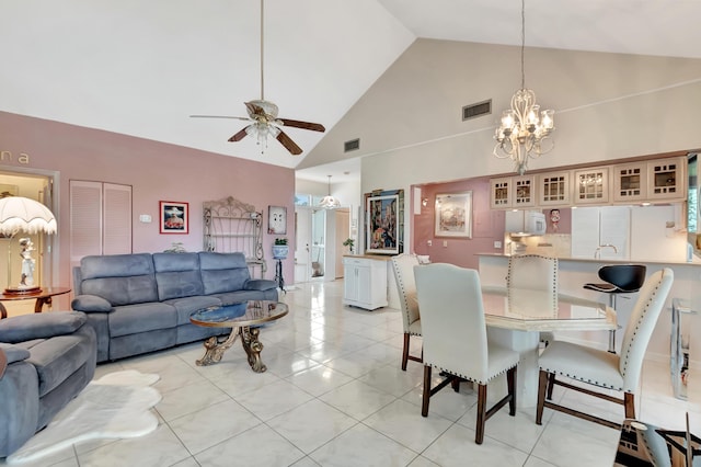 tiled dining room with ceiling fan with notable chandelier and high vaulted ceiling