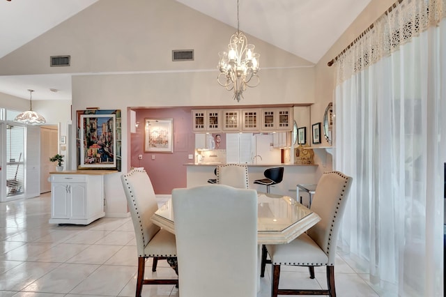 dining space featuring a notable chandelier, light tile patterned floors, and high vaulted ceiling