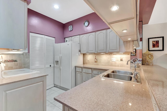 kitchen featuring decorative backsplash, white fridge with ice dispenser, white cabinetry, and sink