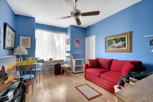 living room with a textured ceiling, light hardwood / wood-style flooring, and ceiling fan