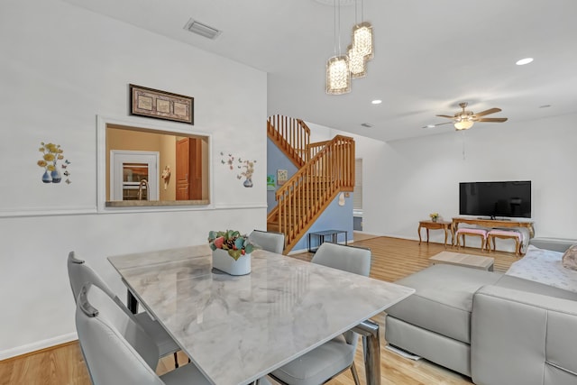 dining room with ceiling fan with notable chandelier and light hardwood / wood-style flooring