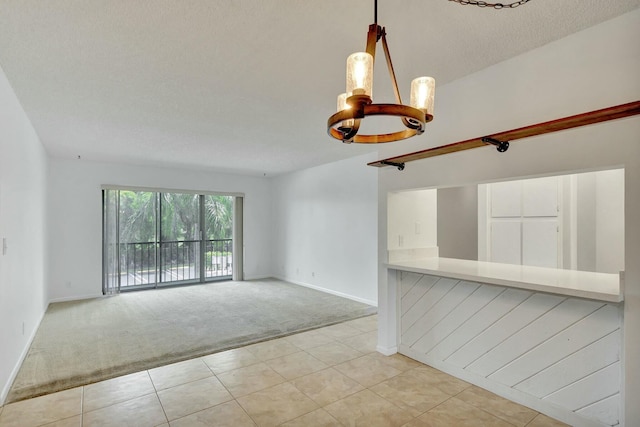 unfurnished room with a textured ceiling, light colored carpet, and an inviting chandelier