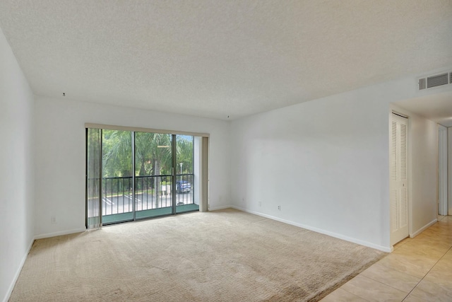 spare room with light colored carpet and a textured ceiling