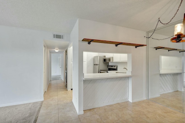 kitchen with sink, stainless steel appliances, white cabinets, a textured ceiling, and light tile patterned floors