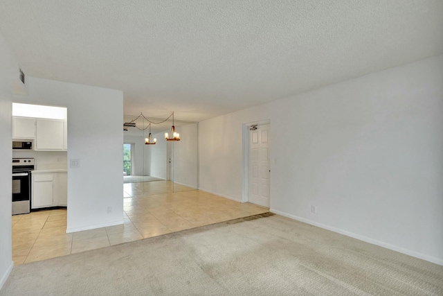 spare room with an inviting chandelier and light tile patterned flooring