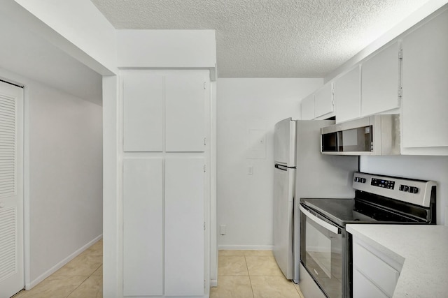 kitchen featuring white cabinetry, light tile patterned floors, stainless steel appliances, and a textured ceiling