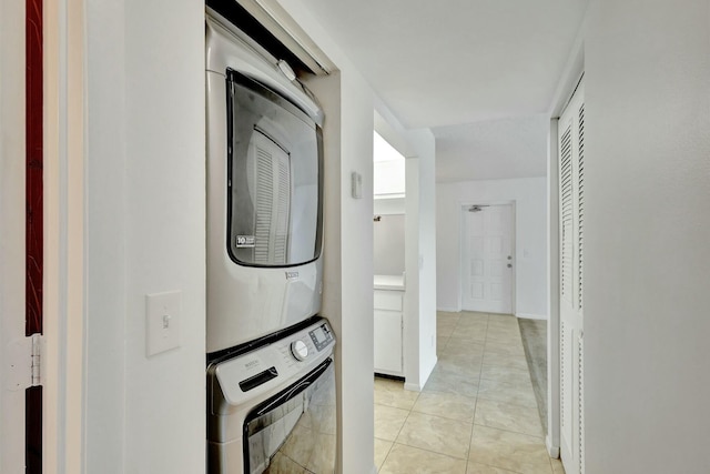 laundry room with stacked washing maching and dryer and light tile patterned floors