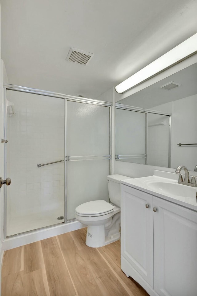 bathroom with hardwood / wood-style flooring, vanity, toilet, and a shower with door