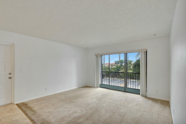 spare room featuring a textured ceiling and light colored carpet