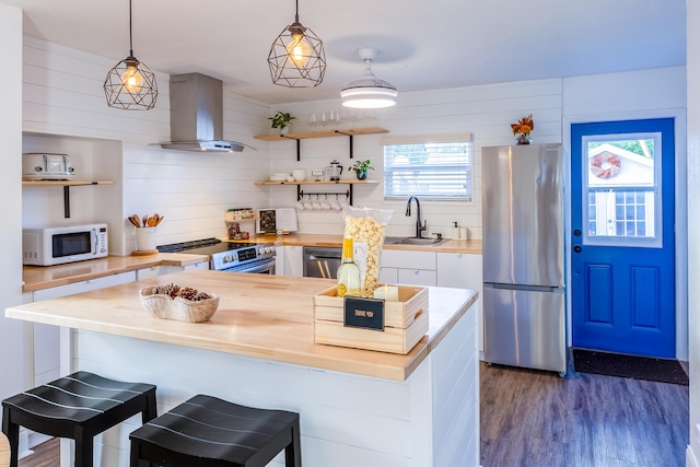 kitchen with wood counters, appliances with stainless steel finishes, extractor fan, sink, and pendant lighting