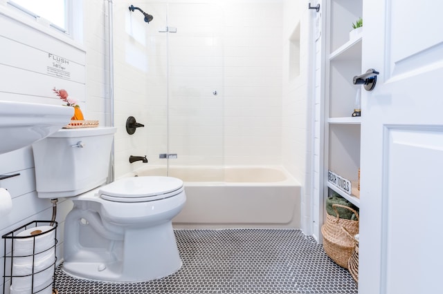 bathroom with wood walls, toilet, and washtub / shower combination