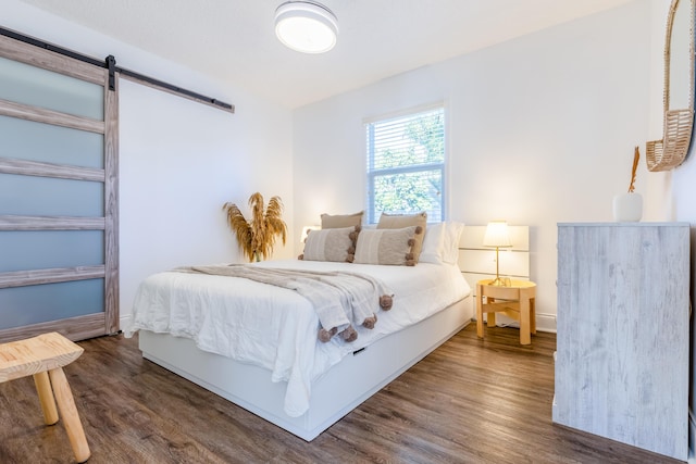 bedroom with a barn door and dark hardwood / wood-style flooring