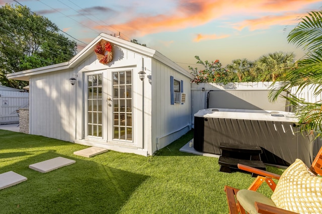 outdoor structure at dusk with a lawn and a hot tub