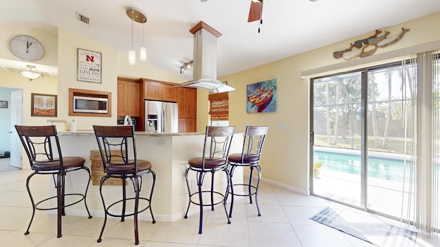 kitchen featuring a breakfast bar, lofted ceiling, hanging light fixtures, and appliances with stainless steel finishes