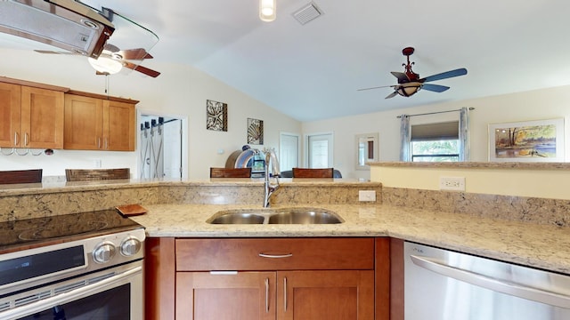 kitchen featuring appliances with stainless steel finishes, light stone counters, lofted ceiling, and sink