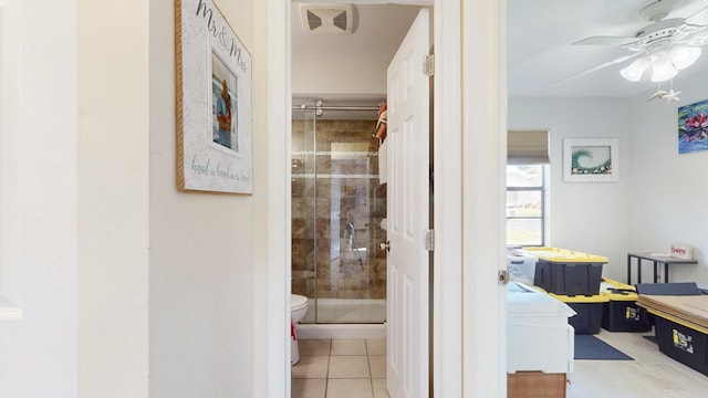 bathroom with tile patterned flooring, ceiling fan, toilet, and walk in shower