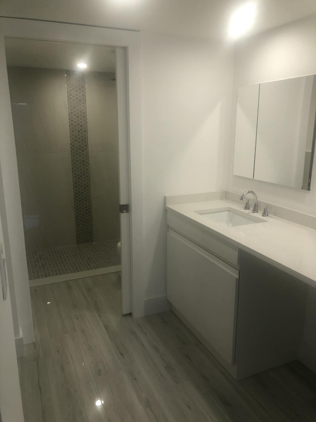 bathroom featuring tiled shower, vanity, and hardwood / wood-style floors