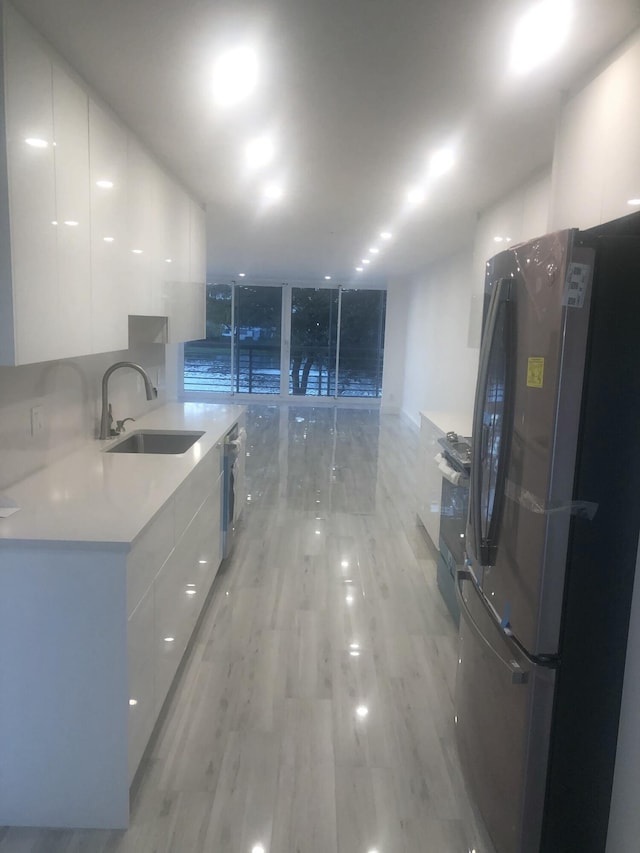 kitchen featuring white cabinetry, appliances with stainless steel finishes, sink, and light hardwood / wood-style flooring