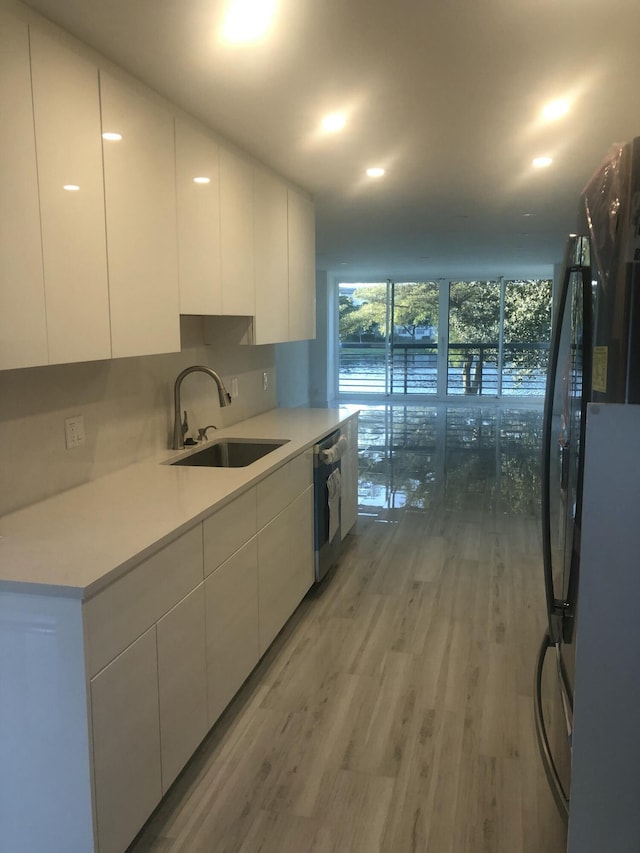 kitchen with white cabinetry, dishwasher, wood-type flooring, and sink