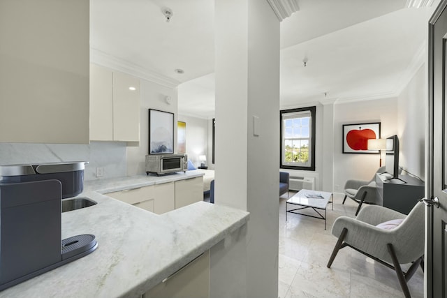 kitchen featuring white cabinets, decorative backsplash, light stone counters, and crown molding