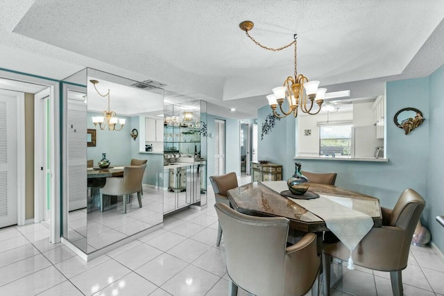 tiled dining space with a tray ceiling, an inviting chandelier, and a textured ceiling