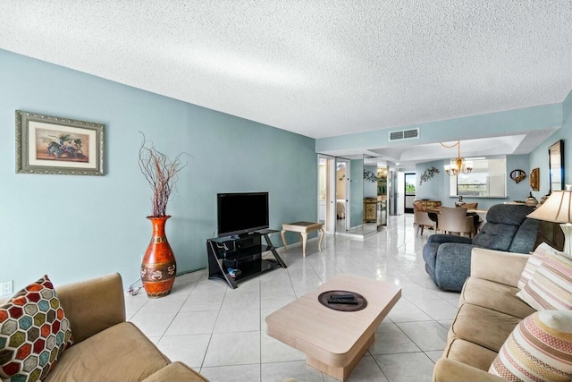 living room with light tile patterned flooring, a textured ceiling, and a notable chandelier