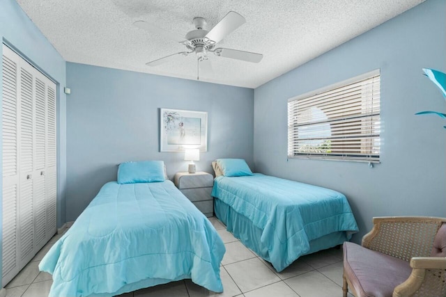 tiled bedroom with ceiling fan, a textured ceiling, and a closet