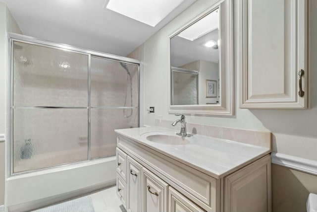 bathroom with bath / shower combo with glass door, vanity, and a skylight