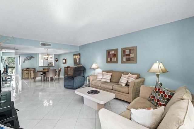 living room featuring an inviting chandelier, light tile patterned floors, and a textured ceiling