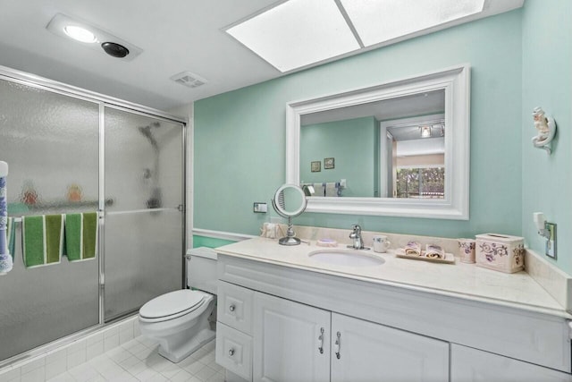 bathroom with tile patterned flooring, toilet, a shower with shower door, a skylight, and vanity