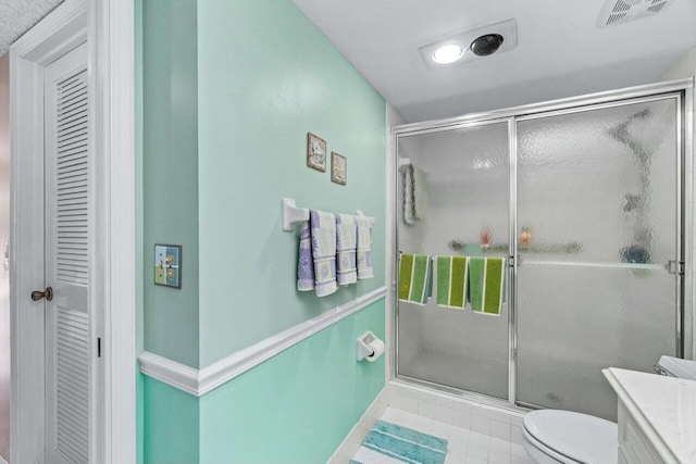 bathroom featuring vanity, tile patterned flooring, toilet, and walk in shower