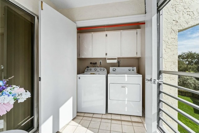 laundry area with cabinets, washer and clothes dryer, and light tile patterned floors