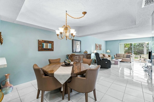 tiled dining space with a tray ceiling, a textured ceiling, and a notable chandelier