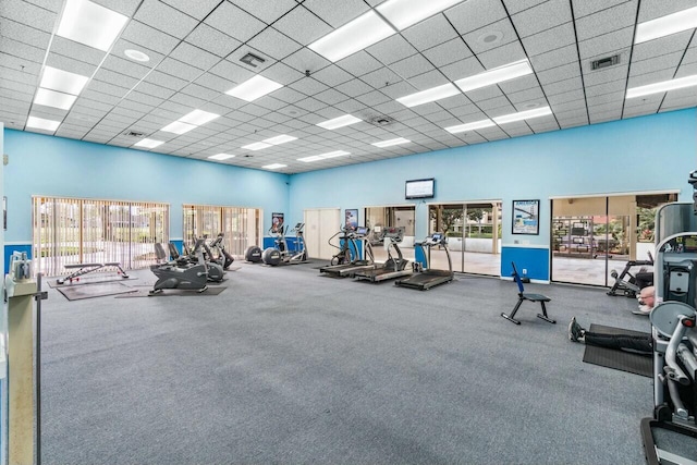 workout area featuring plenty of natural light, a drop ceiling, and a towering ceiling