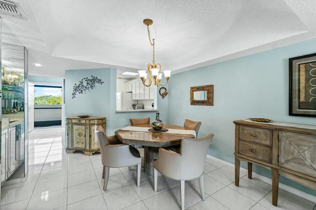 tiled dining space featuring a notable chandelier and a textured ceiling