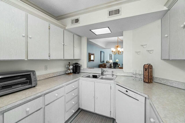 kitchen featuring an inviting chandelier, sink, a textured ceiling, white dishwasher, and hanging light fixtures