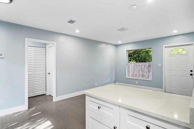 kitchen featuring white cabinets and light stone countertops