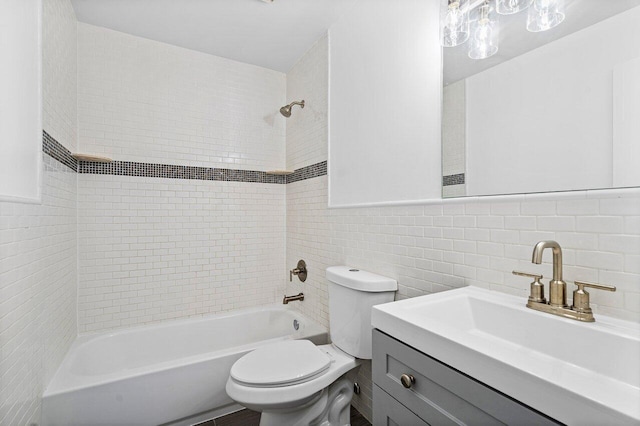 full bathroom featuring vanity, tiled shower / bath combo, tile walls, and toilet