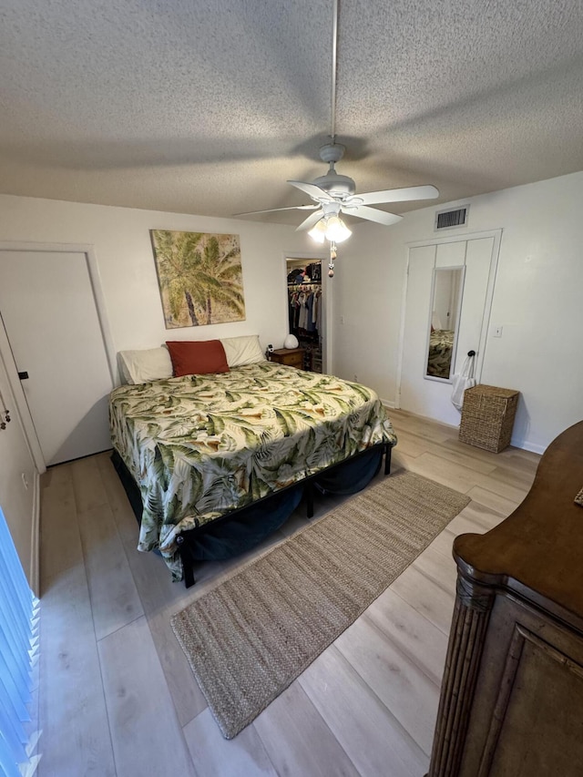 bedroom with ceiling fan, light hardwood / wood-style floors, and a textured ceiling