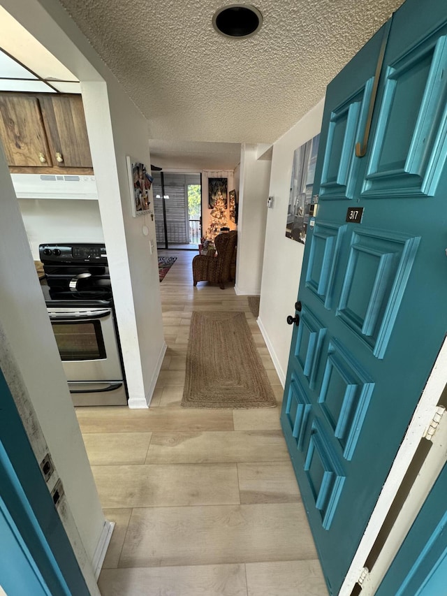 hallway with a textured ceiling and light wood-type flooring