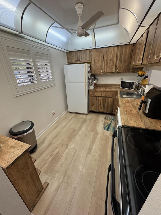 kitchen with stove, white refrigerator, sink, ceiling fan, and light wood-type flooring