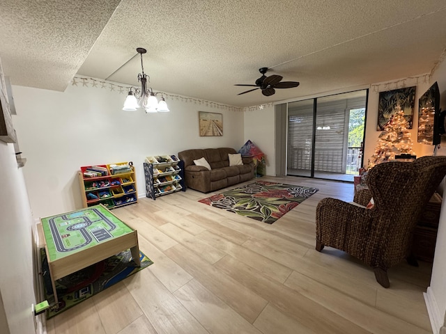 living room with hardwood / wood-style flooring, ceiling fan with notable chandelier, and a textured ceiling