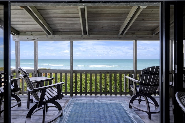 sunroom / solarium with beamed ceiling, a water view, wooden ceiling, and a beach view