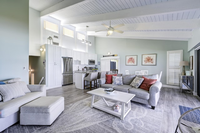 living room featuring beamed ceiling, high vaulted ceiling, light hardwood / wood-style flooring, and ceiling fan