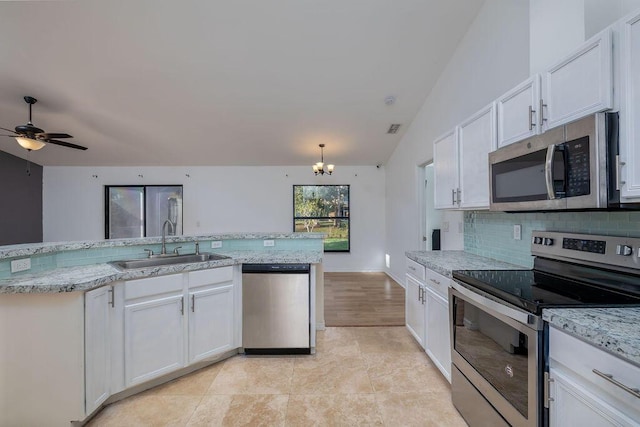 kitchen featuring sink, decorative backsplash, white cabinets, ceiling fan with notable chandelier, and appliances with stainless steel finishes