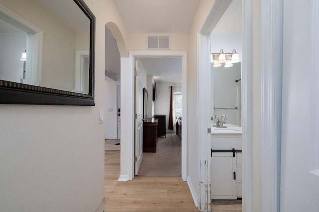 hallway with a barn door, sink, and light hardwood / wood-style flooring