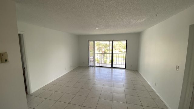 empty room with light tile patterned floors and a textured ceiling