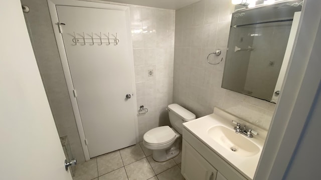 bathroom featuring tile patterned flooring, vanity, toilet, and tile walls