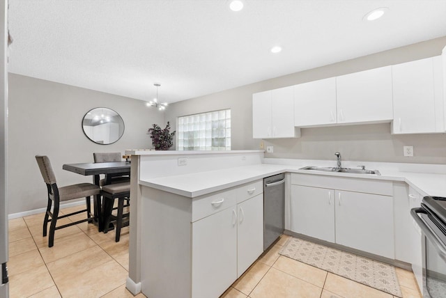 kitchen with kitchen peninsula, appliances with stainless steel finishes, white cabinets, and sink